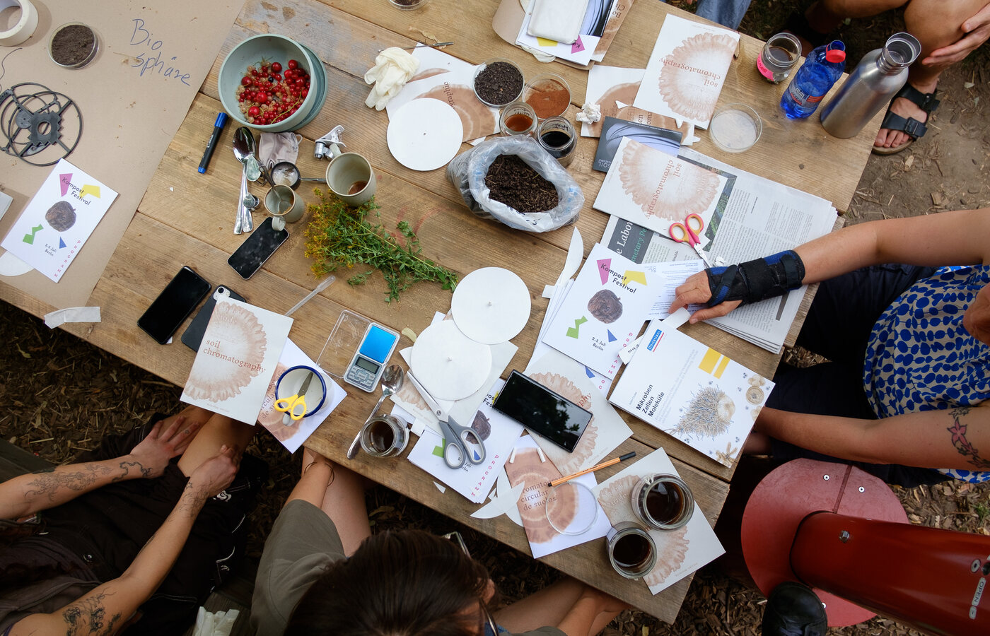 Manos y materiales sobre una mesa durante un taller colectivo de cromatografía de suelos